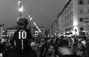Black and white image of behind a crowd of sports fans lining the streets in France.
