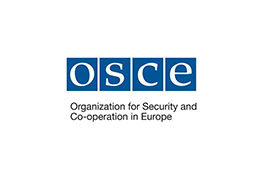Le logo de l'Organisation pour la sécurité et la coopération en Europe - quatre carrés bleus avec le texte blanc «OSCE» à l'intérieur, sous lequel se trouve le texte noir «Organisation pour la sécurité et la coopération en Europe».