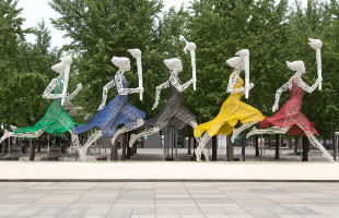 Escultura olímpica de 5 mujeres corriendo con antorcha olímpica