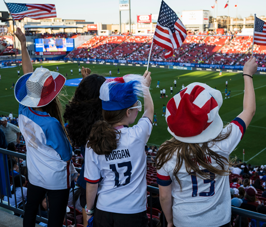 Niños simpatizantes de US Soccer ondean banderas estadounidenses en un estadio
