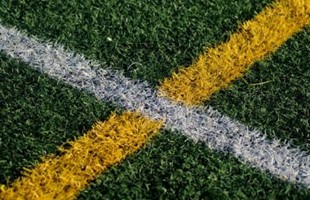 Close up image of painted lines on grass sports pitch.