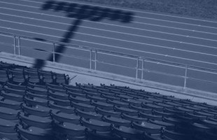 El respaldo de las sillas vacías del estadio deportivo frente a la pista de atletismo.